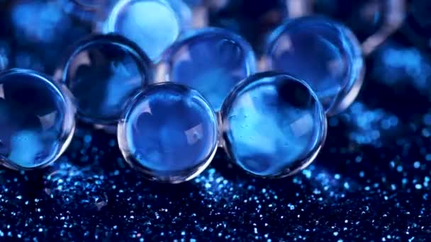 水晶凝胶水球在蓝色闪光纹理旋转 关闭宏镜头 — 图库视频影像