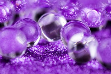Crystal jel su topları üzerinde mor glitter doku döndürme. Makro görüntüleri kapat.