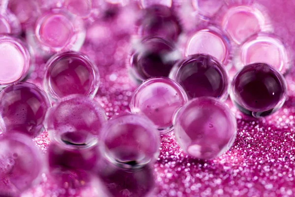 Crystal jel su topları üzerinde pembe glitter doku döndürme. Makro görüntüleri kapat.