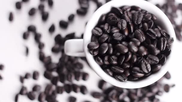 Siyah Kahve Çekirdekleri Beyaz Fincan Beyaz Yüzey Üzerinde Döner Yakın — Stok video