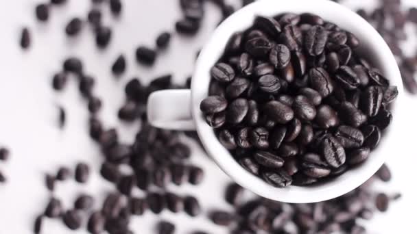 Grãos Café Preto Copo Branco Girando Superfície Branca Fechar — Vídeo de Stock