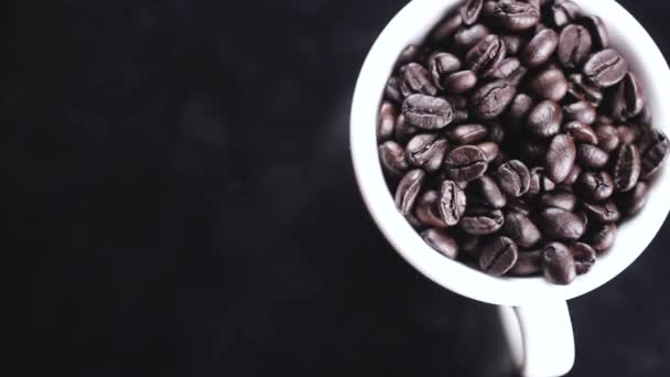 Mörka Kaffebönor Vit Kopp Roterande Svart Yta — Stockvideo