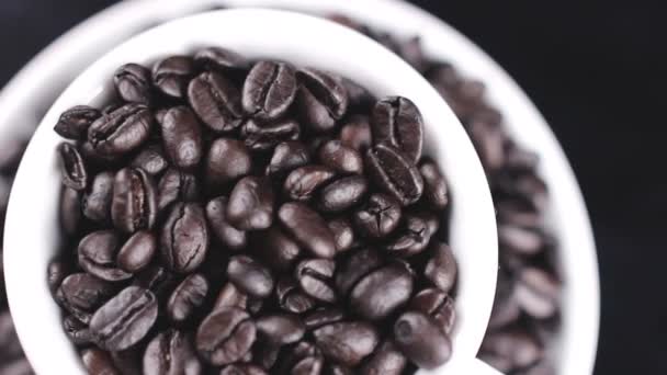 黑咖啡豆在白色盖帽和板材旋转在黑暗的背景 — 图库视频影像