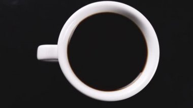 Beyaz fincan koyu yüzey üzerinde dönen siyah kahve.