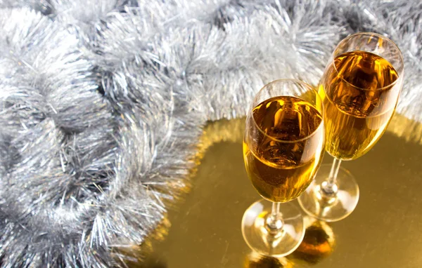 Two champagne or wine glasses with gold and silver christmas tinsel decoration.