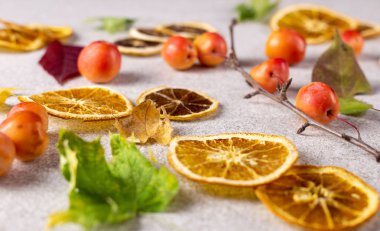 Kurutulmuş dilimlenmiş limon ve portakal ile taze kırmızı elma ve sonbahar yaprakları beyaz doku yüzeyine.