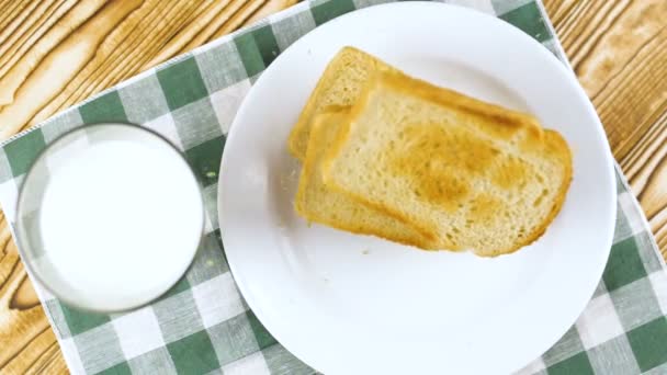 烤面包落在白色盘子里 牛奶在木制厨房表面的玻璃 慢镜头 — 图库视频影像