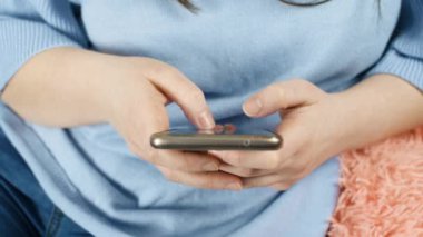 Genç kız telefon ve kanepede koltukta mesaj manifatura. Yavaş hareketi kapatın. 4k görüntüleri.