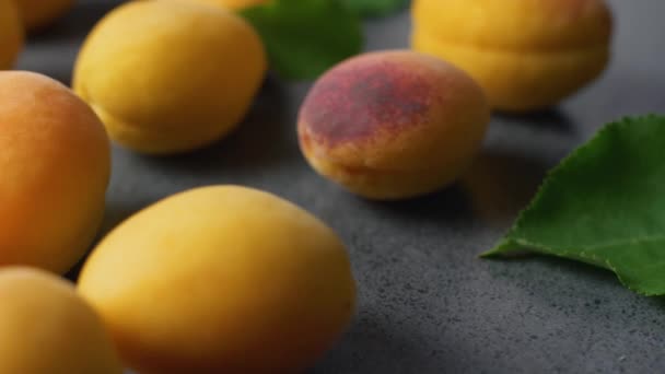美味的新鲜切片杏子与绿色的树叶在黑暗的纹理表面 夏季水果 — 图库视频影像