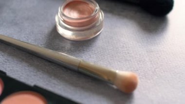 Kadın kozmetik gümüş doku yüzeyinde makyaj. Göz farları palet ve farklı renk tozları ile fırçalar. 4k.
