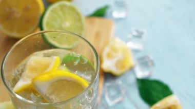 Limon ve limon ile giriş cam düşen yavaş hareket dilimlenmiş narenciye kapatın. Buz küpleri ile taze coctail doğrama tahtası üzerinde kalmak. Yaz içkisi.