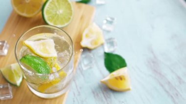 Limon ve limon ile giriş cam düşen yavaş hareket dilimlenmiş narenciye kapatın. Buz küpleri ile taze coctail doğrama tahtası üzerinde kalmak. Yaz içkisi.