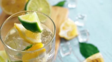 Limon ve limon ile giriş cam düşen yavaş hareket dilimlenmiş narenciye kapatın. Buz küpleri ile taze coctail doğrama tahtası üzerinde kalmak. Yaz içkisi.