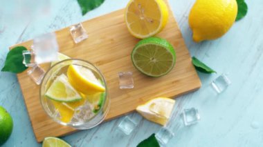 Dilim kireç ve limon ile buz düşen giriş cam yavaş hareket kapatın. Taze coctail doğrama tahtasıüzerinde kalmak. Yaz içkisi.