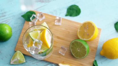 Dilim kireç ve limon ile buz düşen giriş cam yavaş hareket kapatın. Taze coctail doğrama tahtasıüzerinde kalmak. Yaz içkisi.