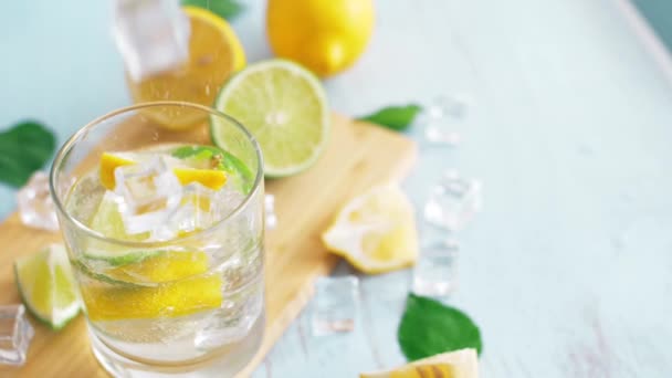 特写冰块的慢动作 玻璃上贴着片石灰和柠檬 新鲜的科尾留在切碎板上 夏季饮料 — 图库视频影像