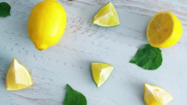 Mavi ahşap doku yüzeyinde yeşil yaprakları ile taze dilimlenmiş kireç ve limon kapatın. Mutfakta 4k narenciye. 