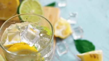 Dilim kireç ve limon ile buz düşen giriş cam yavaş hareket kapatın. Taze coctail doğrama tahtasıüzerinde kalmak. Yaz içkisi.