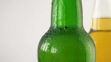 Beyaz izole arka plan üzerinde su damlaları ile bira iki şişe. Şeffaf ve yeşil şişelerde alkol olabilir 4k yakın.