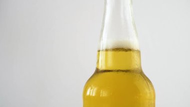 Taze bir şişe beyaz arka plan üzerinde dönen su damlaları ile bira olabilir. 4k yavaş çekim görüntüleri.