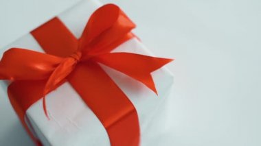 Kırmızı ipek kurdele dönen beyaz hediye kutusu. Noel, kara cuma ve diğer tatiller için hediye kutusu. 4k görüntüleri kapatın.