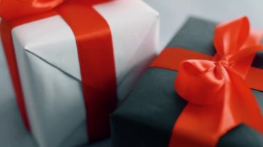 Beyaz arka plan üzerinde dönen kırmızı ipek kurdele ile siyah ve beyaz hediye kutusu. Noel, kara cuma ve diğer tatiller için hediye kutuları. 4k görüntüleri kapatın.