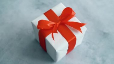 Kırmızı ipek kurdele dönen beyaz hediye kutusu. Noel, kara cuma ve diğer tatiller için hediye kutusu. 4k görüntüleri kapatın.