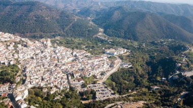 İspanya 'nın güneyinde Marbella' nın yanında dağlarla yeşil bitkiler arasında bir kasabanın havadan çekilmiş fotoğrafı.