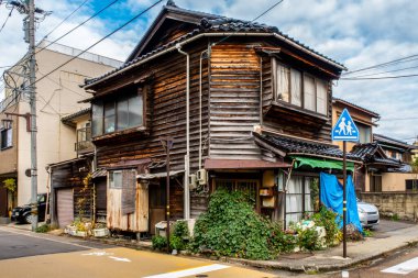 Japonya, Kanazawa 'da terk edilmiş eski ahşap bir hayalet ev. Japon oyma çatısı, fazla gelişmiş bitkiler ve çöp yığını var..