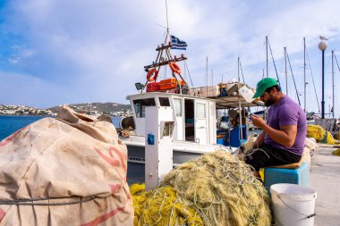 FINIKAS, SIROS, Yunanistan, 27 / 05 / 2019. Yunan balıkçı, Yunanistan 'ın Cyclades kentindeki Siros Adası' ndaki Finikas Limanı 'ndaki iskelede naylon balıkçı ağlarını onarıyor.