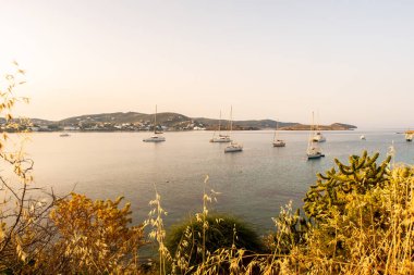 Finikas Limanı 'ndaki Anchorage, karadan gün doğumundan sonra sabah görüşü. Birçok yelkenli sakin bir körfeze demir attı. Siros Adası, Yunanistan.
