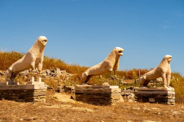 DELOS Adası 'ndaki antik üç taş aslan heykeli - Yunanistan' daki mitolojik, tarihi ve arkeolojik alan. Mavi gökyüzü arkaplanındaki orijinal heykellerin kalıntıları.