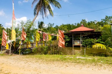 Pulau Ubin Adası, Singapur 'daki Wei Tuo Fa Gong Budist Tapınağı' nda yeşil tropikal doğa arasında renkli Budist bayrakları, göleti ve tapınağı vardır..