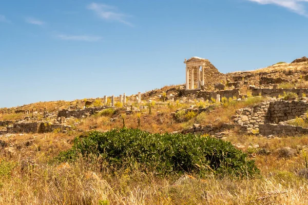 Well preserved Temple of Isis on Delos Island located on the hill above the ancient city with other ruins and blue sky in the background, Greece.