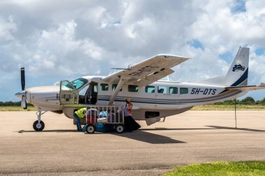 Pemba, Tanzanya, 28 / 09 / 18. Auric Air yerel havayolu şirketi Cessna 208 ile Pemba Yurtiçi Havalimanı önlüğü bagaj yükleme ve yerli uçuş için hazırlık.