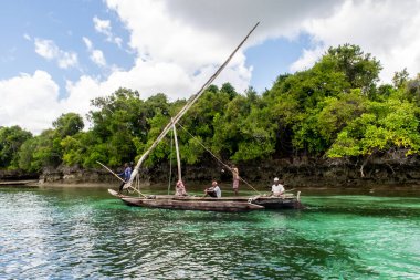 Pemba Adası, Tanzanya, 28 / 09 / 18. Dhow - ahşap swahili kültürü geleneksel teknesi Pemba Adası, Hint Okyanusu kıyısında yerel balıkçıyla birlikte. Arka planda tropik orman, masmavi berrak su.