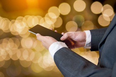 Bulanık altın sarısı arka plan, iş ve iletişim üzerinde akıllı telefon aygıtı kullanan bir işadamı.