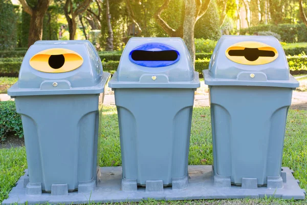 Parkta güneş ışığıyla geri dönüşüm kutuları.