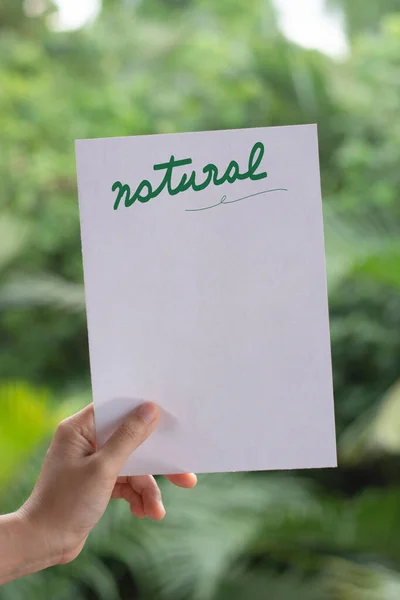 人类手拿着带有自然文字和自然背景的纸便条 — 图库照片
