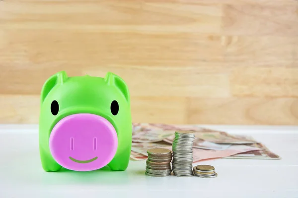 Sırıtan domuz kumbarası ahşap duvarlı bozuk para yığını.