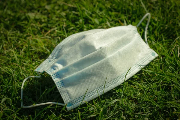 Flu epidemic, self-isolation and coronavirus protection concept. Medical face mask in the grass. Social distancing to prevent spread of COVID-19 coronavirus in the New Normal.