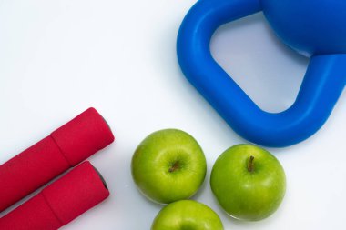 Mavi halterler, kırmızı halterler ve gölgeli yeşil elmalar. 