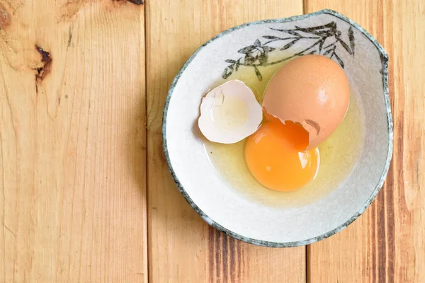 Cracked eggs with egg shells, egg yolks and eggs in a ceramic bowl
