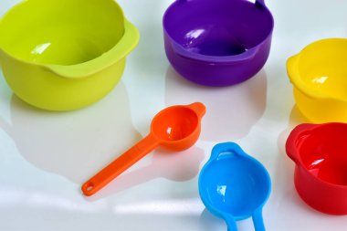 Renkli plastikten yapılmış bir kaşık seti. Plastik ölçüm kaşıkları yakın çekim, mutfak ekipmanları beyaz arka planda