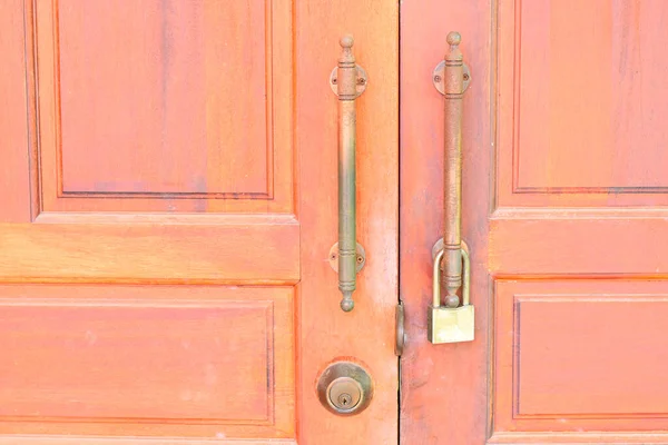 The keys are hanging on the handle of the old red wooden door.