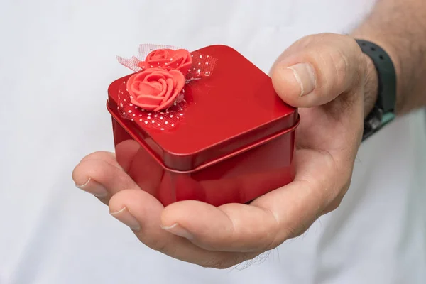 Red gift box with flowers in man's hand