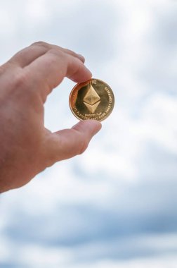Ethereum altın mavi gökyüzü arka plan üzerinde elinde