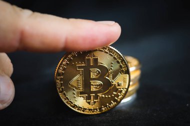 parmağını sikke altın sikke bitcoin bir yığın üzerinde tutar