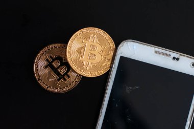 bitcoin ve dolar ve cep telefonu siyah arka plan üzerine iki altın sikke