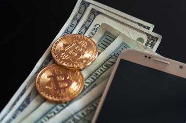 bitcoin ve dolar ve cep telefonu siyah arka plan üzerine iki altın sikke